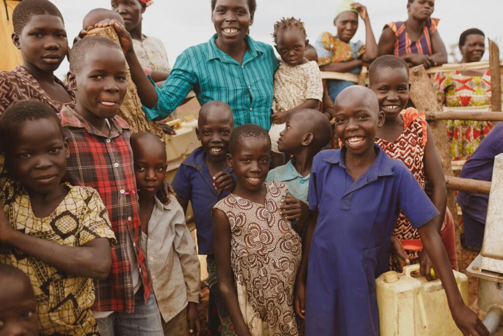 Group of smiling children in Gulu, Uganda, capturing happiness and community spirit outdoors.