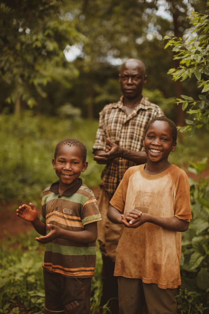 Smiling family in a lush, rural landscape in Masindi, Uganda.